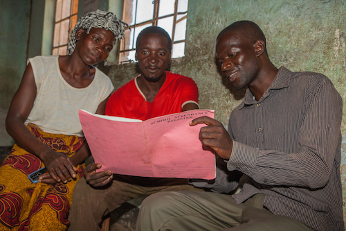 Malawi child marriage - mother and father group checking school attendance register picture by Tearfund/Chris Hoskins