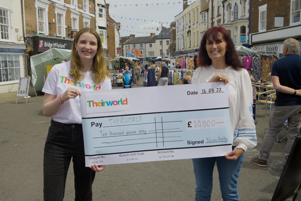 Nicola Haxby presents Emma Wace from Theirworld's fundraising team with a check for £10,000, the total amount raised by her tireless fundraising work.