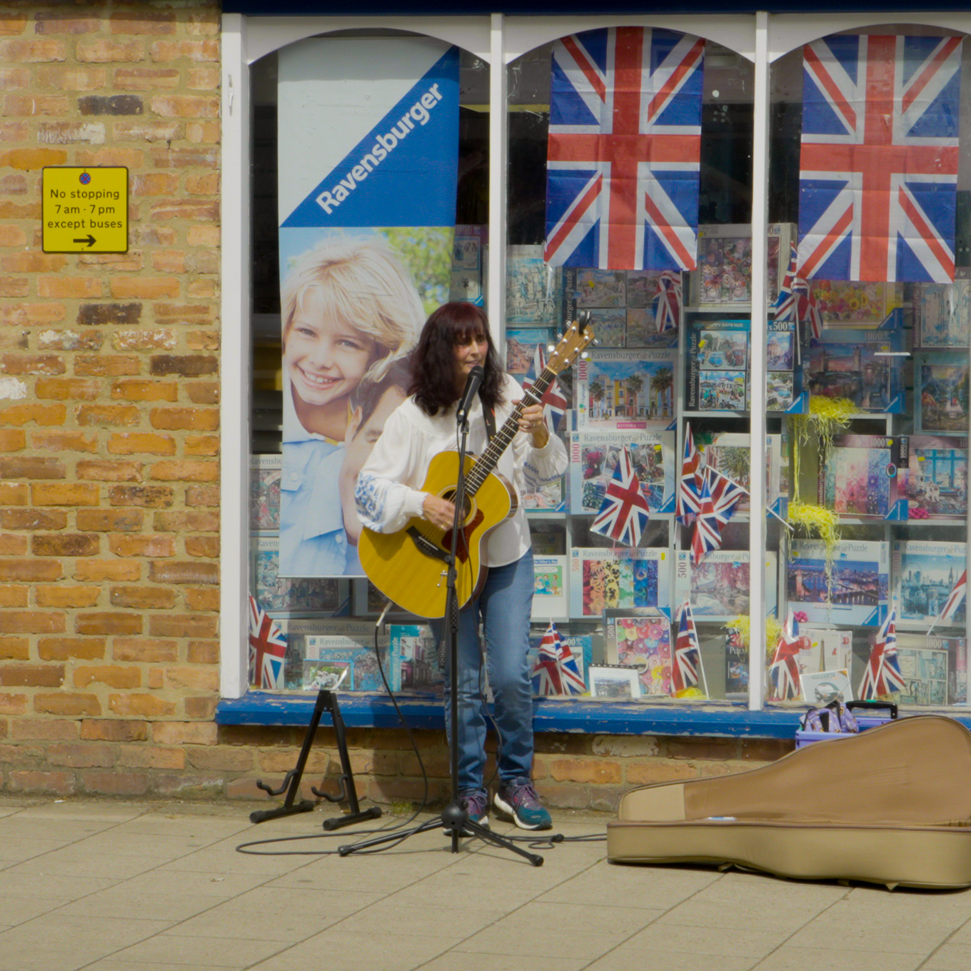 Nicola Haxby busking on the street with her guitar and microphone.