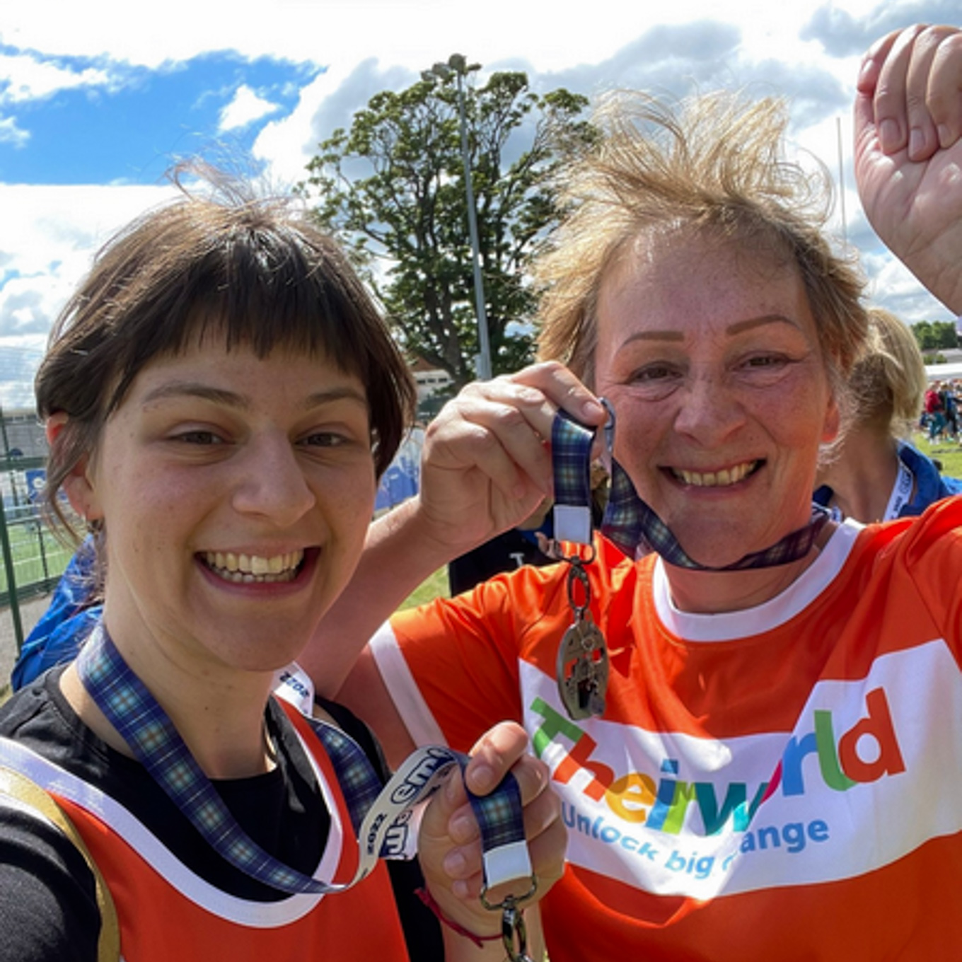Two runners wearing their medals and Theirworld shirts after running.