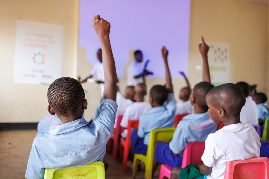 Children in a classroom with their hands raised