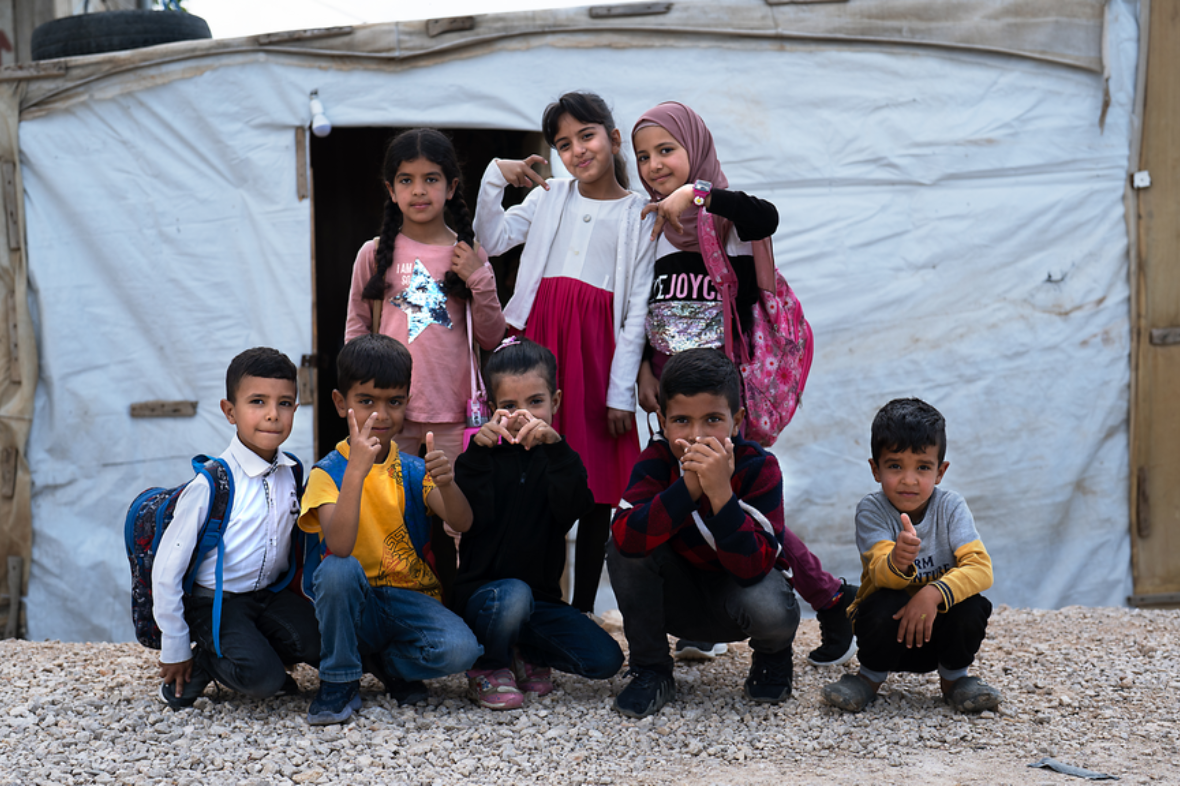 Syrian children pose for a photo at an informal tented settlement 