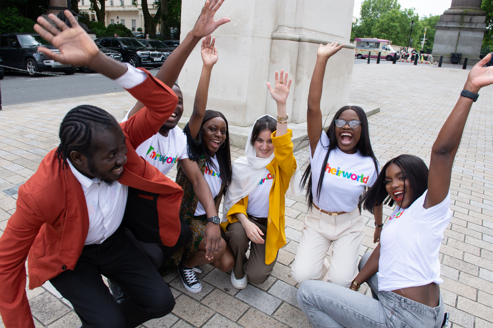 Six Theirworld Global Youth Ambassadors raising their hands to the camera
