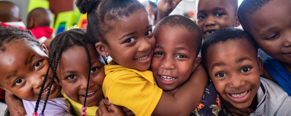 A group of children hugging and looking at the camera